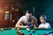 Father and son play billiards. The father teaches his son to play billiards. The concept of parents and children, upbringing,