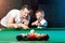 Father and son play billiards. The father teaches his son to play billiards. The concept of parents and children, upbringing,