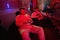 Father and son play gamepad video game console in red gaming room. Dad and kid gamers