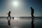 Father and son play soccer or football on the beach. Dad and child playing outdoor, silhouette on sunset. Active family