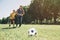 Father and son are playing football. They are running together. Boys want to reach the ball first.