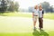 Father and son playing golf. Full length of father and son standing on golf course with arms around.