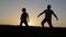 Father and son playing soccer in the park at the sunset time.