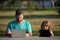 Father and son playing or studying with laptop in the park. Kid with daddy learning lesson. Blogging.