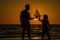 Father and son playing with toy ship on sea. Sunset silhouette of father son dreaming on cruise. Dreaming to travel