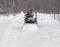 Father and son plow a snowy drive on a tractor