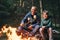 Father and son roast marshmallow candies on the campfire in fore