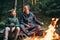 Father and son roast marshmallow candies on the campfire in fore