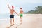 Father and son in Santa`s hats run on perfect sand beach on trop