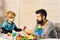 Father and son with serious faces play with toy bricks