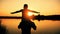 Father and son silhouettes playing on beach boy rising up hands imitating a flight at wonderful sunset through the