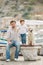 Father and son sits with dogs on a bench near the sea