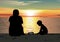 Father and son sitting on the beach, watching sunset