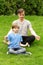 Father and son sitting on grass and meditates