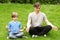 Father and son sitting on grass and meditates
