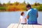 Father and son sitting on pier by the lake on sunny summer day