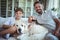 Father and son sitting on sofa with pet dog and watching television