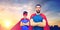 Father and son in superhero capes over city