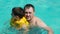 Father and son swim in the pool, a child in an inflatable vest. Family vacation.