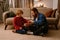 Father and son unwrapping present while sitting on floor at home