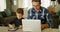 Father and son using laptop and digital tablet in living room 4k