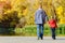 Father and son are walking along the pier. Autumn, sunny. Back v