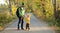 Father and son walking together on empty road in autumn park, enjoying good weather. Beautiful nature in fall season. Parenting