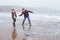 Father And Son Walking On Winter Beach And Throwing Stones