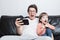 Father and son watching a scary video on the phone sitting on a sofa on a white background. They`re screaming. A little boy and