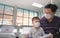 Father and son wearing protective medical mask in public area, sitting with distance during covid-19 virus outbreak, Social