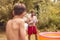 Father And Son Wearing Swimming Costumes Having Water Fight With Water Pistols In Summer Garden