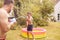 Father And Son Wearing Swimming Costumes Having Water Fight With Water Pistols In Summer Garden