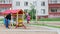 Father swings little daughter and son on seesaw at playground in cloudy day