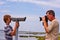 Father takes a picture of his son looking thru a telescope