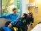 Father talking with disabled son in wheelchair at hopsital room