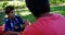 Father talking to son at picnic in park 4k