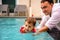 Father teaches cute toddler little girl in swimsuit to swim in the pool holding his hand
