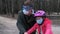 A father teaches his daughter to ride a Bicycle in a city Park. they are wearing protective helmets and medical masks. The concept