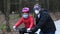 A father teaches his daughter to ride a Bicycle in a city Park. they are wearing protective helmets and medical masks. The concept