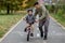 Father teaches his son to ride a bicycle on the bike path in the park. The father is holding a bicycle and the son is sitting on