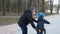 A father teaches his son to ride a Bicycle in a city Park. they are wearing protective helmets and medical masks. The concept of
