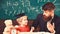 Father teaches son mathematics. Arithmetic lesson concept. Teacher in formal wear and pupil in mortarboard in classroom