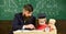 Father teaches son mathematics. Mathematics lesson concept. Teacher in formal wear and pupil in mortarboard in classroom