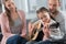 Father teaching daughter how to play acoustic guitar while mother is sitting with them