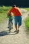 Father teaching daughter to ride a bicycle on a dusty country road