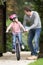 Father Teaching Daughter To Ride Bike In Garden