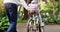 Father teaching his child to ride a bicycle on a path in an outdoor green community park. Love, bonding and closeup of a