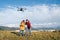 Father and Teenager boy son dressed yellow jacket piloting a modern digital drone using remote controller. Modern technology
