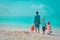 Father with three kids play on beach, family at sea