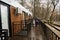 Father with three kids on terrace of one-storey modular houses in spring rainy forest